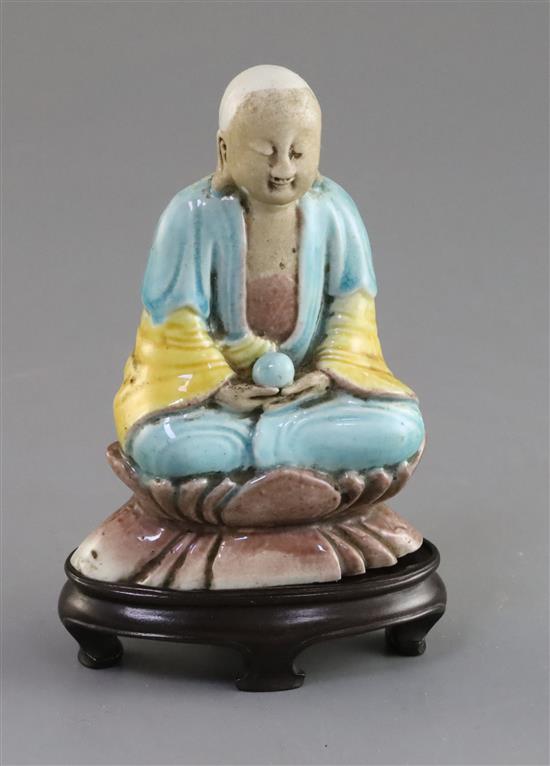 A Chinese enamelled biscuit seated figure of Buddha, 18th/19th century, H. 9.5cm, wood stand